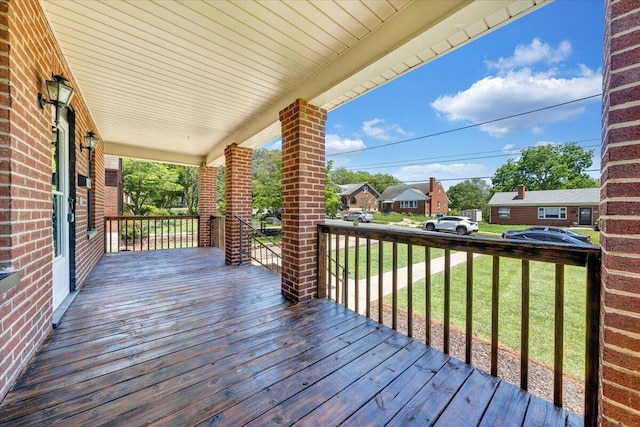 wooden terrace featuring covered porch, a yard, and a residential view