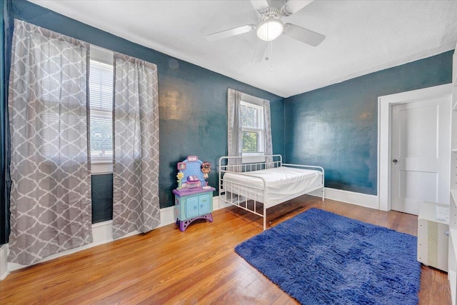 bedroom featuring wood finished floors, baseboards, and ceiling fan