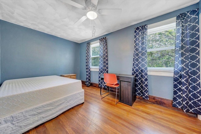 bedroom featuring light wood-style flooring, baseboards, and a ceiling fan