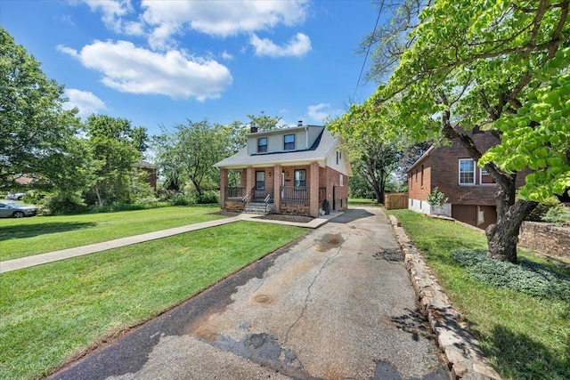 bungalow-style home with brick siding, asphalt driveway, a front lawn, covered porch, and a chimney