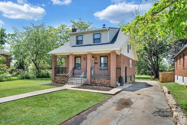 view of front of house with a porch, a chimney, brick siding, a shingled roof, and asphalt driveway