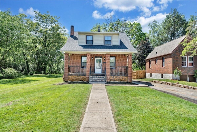 bungalow with a chimney, a porch, a front lawn, and brick siding