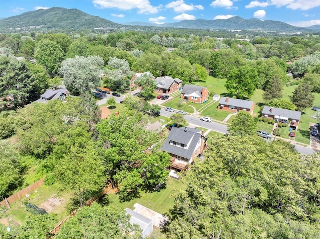 view of property location featuring a mountainous background, nearby suburban area, and a heavily wooded area