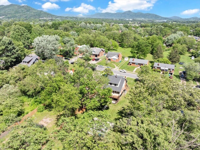 drone / aerial view of a heavily wooded area and a mountainous background