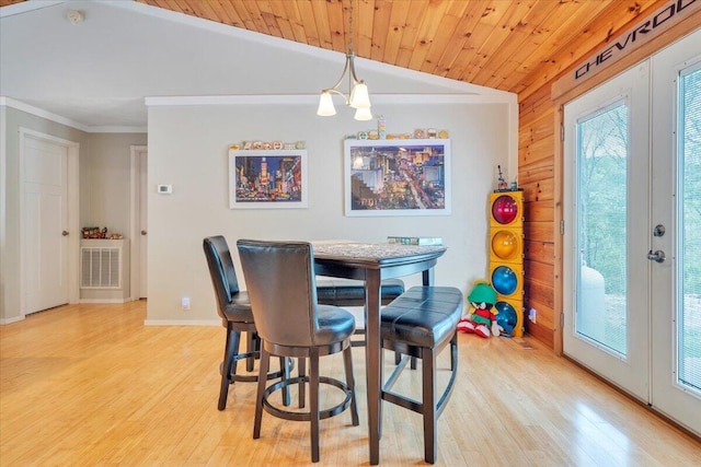 dining room featuring vaulted ceiling, ornamental molding, french doors, light wood-type flooring, and baseboards