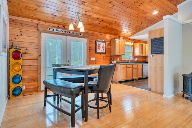 dining area featuring vaulted ceiling, light wood-style floors, french doors, wooden ceiling, and wood walls