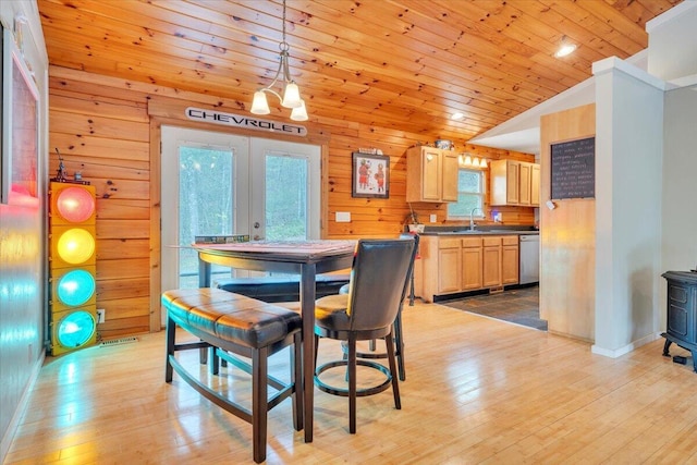 dining room featuring lofted ceiling, light wood-style flooring, wooden walls, and wood ceiling