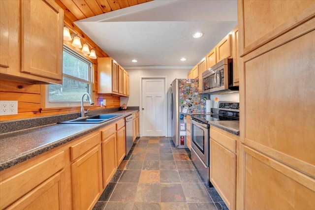 kitchen featuring recessed lighting, stainless steel appliances, stone finish floor, dark countertops, and a sink