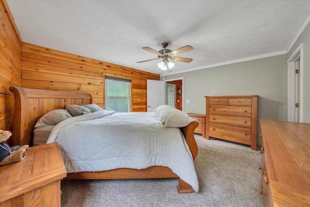 carpeted bedroom with a ceiling fan, wood walls, and ornamental molding
