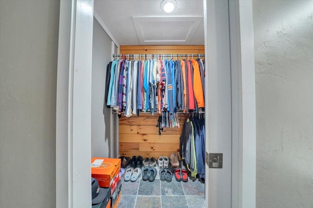 spacious closet with attic access and stone finish flooring