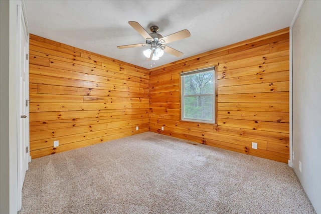 carpeted empty room featuring wood walls and ceiling fan