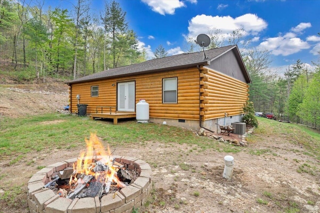 rear view of property featuring central AC, log exterior, a deck, crawl space, and an outdoor fire pit