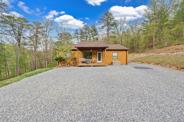 view of front of property featuring driveway, roof with shingles, and log exterior