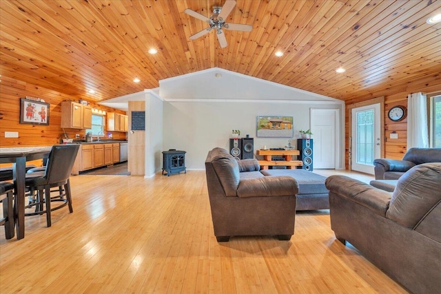 living room with lofted ceiling, plenty of natural light, wood ceiling, and a wood stove