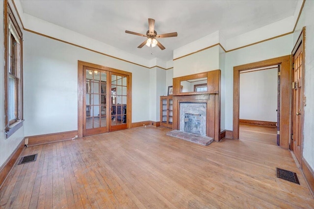 unfurnished living room with wood-type flooring, baseboards, a stone fireplace, and visible vents