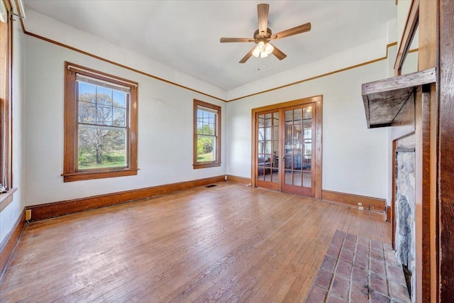 unfurnished living room featuring wood-type flooring, baseboards, a healthy amount of sunlight, and french doors