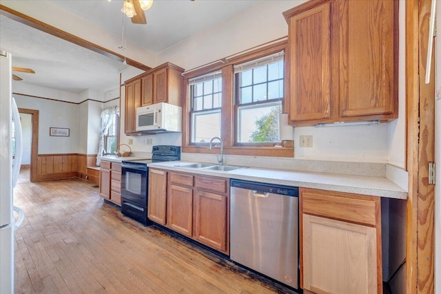 kitchen featuring light wood finished floors, a sink, electric range, white microwave, and dishwasher