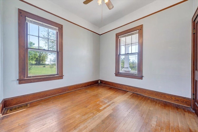 empty room featuring wood-type flooring, baseboards, visible vents, and plenty of natural light