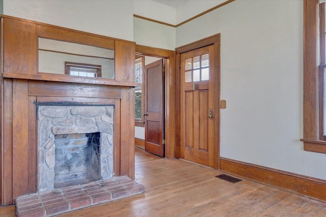 interior space featuring baseboards, wood finished floors, visible vents, and a fireplace