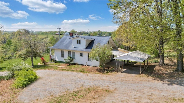 view of front of property with dirt driveway and a detached carport
