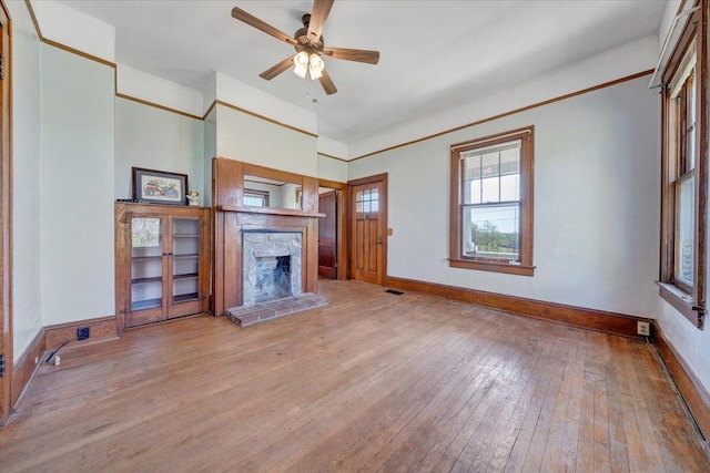 unfurnished living room featuring a fireplace, hardwood / wood-style floors, baseboards, and ceiling fan
