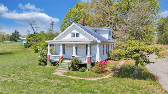 bungalow featuring a porch, a chimney, and a front yard