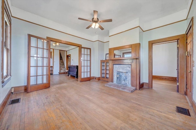 unfurnished living room featuring a fireplace with raised hearth, french doors, visible vents, and light wood-type flooring