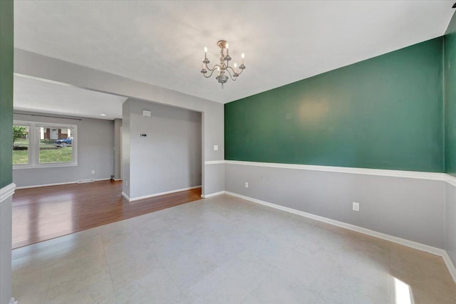 unfurnished room with an inviting chandelier and baseboards