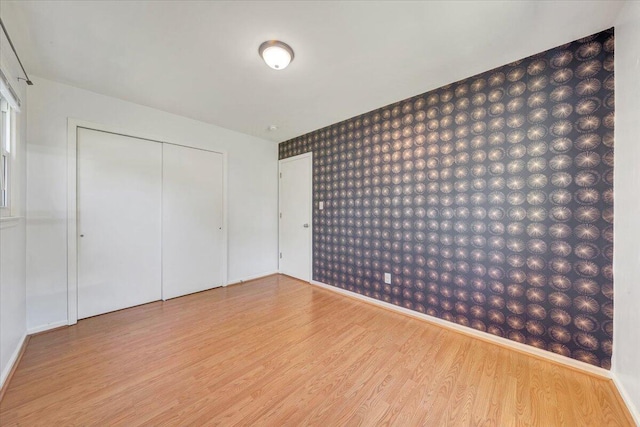 unfurnished bedroom featuring baseboards, wood finished floors, and a closet
