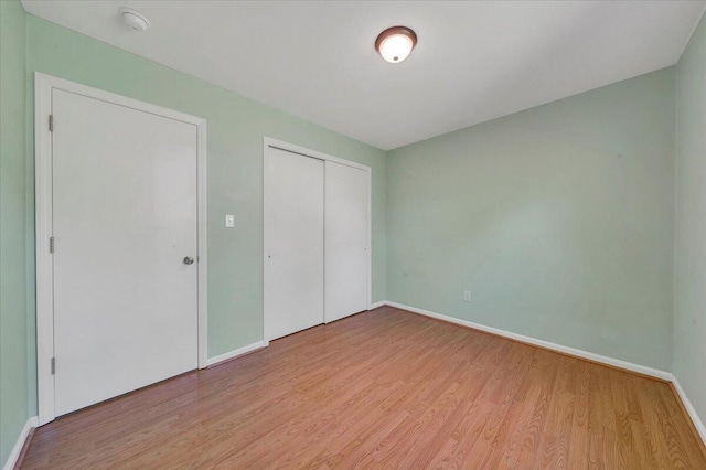 unfurnished bedroom with wood finished floors, a closet, and baseboards