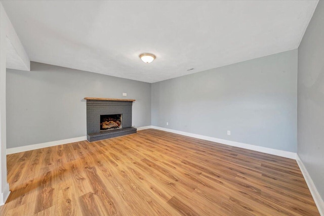 unfurnished living room with a fireplace, baseboards, and light wood-style floors