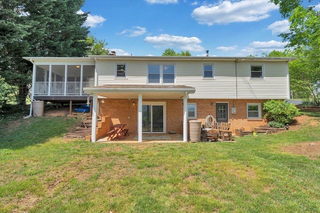 back of property featuring a sunroom, brick siding, a yard, and a patio area