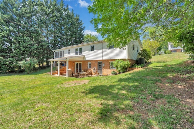 back of property featuring a lawn, central AC, a patio area, and brick siding