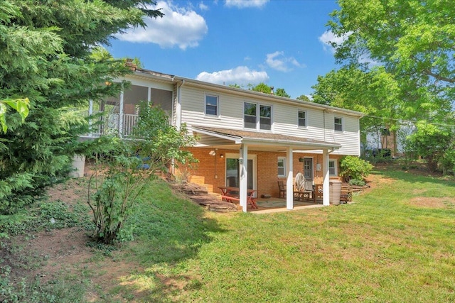 rear view of house with brick siding, a yard, and a patio area
