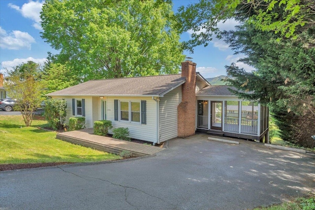 ranch-style home with a chimney and a front lawn