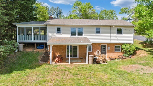 back of property with a chimney, a yard, brick siding, a sunroom, and a patio area