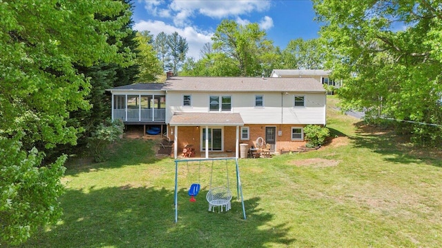 rear view of house featuring a chimney, brick siding, a sunroom, and a lawn