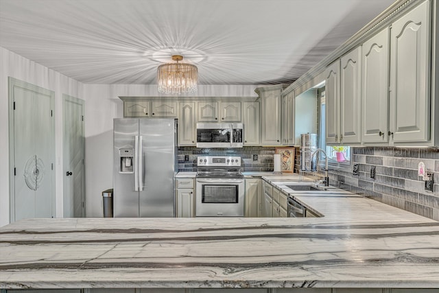 kitchen featuring a sink, appliances with stainless steel finishes, a chandelier, and tasteful backsplash