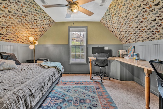 carpeted bedroom with a ceiling fan, visible vents, wainscoting, and vaulted ceiling