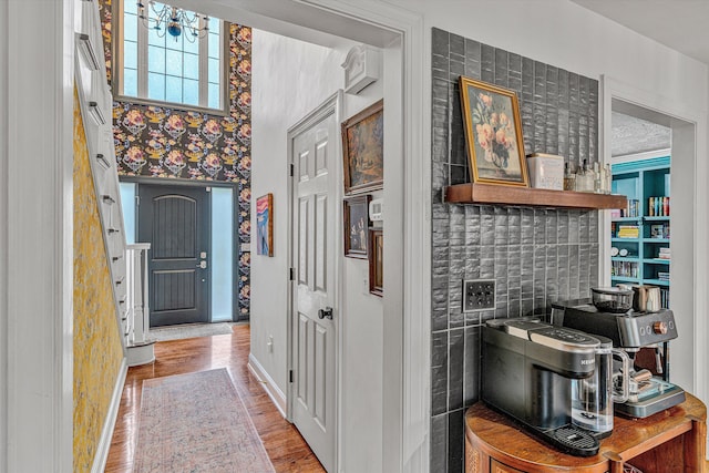 foyer with baseboards, wallpapered walls, and wood finished floors