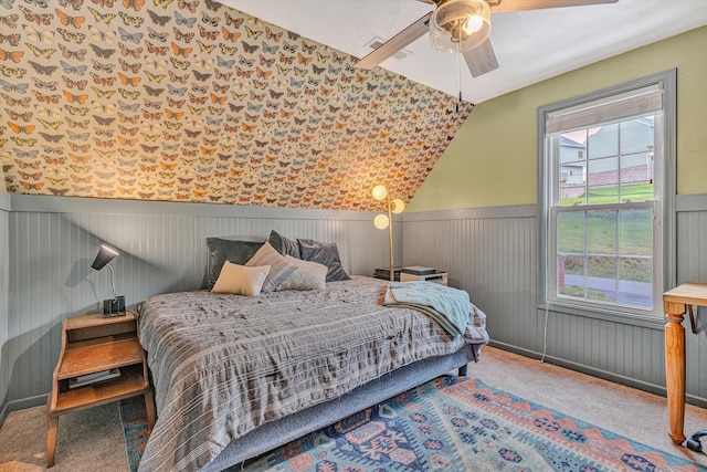 carpeted bedroom with lofted ceiling, a ceiling fan, and wainscoting
