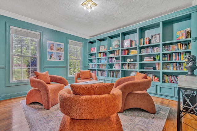 sitting room featuring a textured ceiling, wood finished floors, and ornamental molding