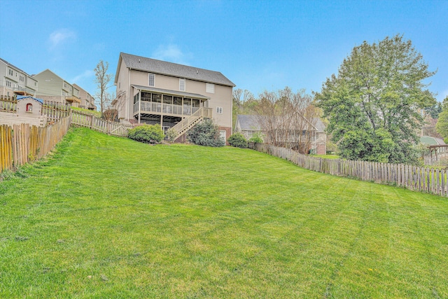 view of yard featuring a fenced backyard, a sunroom, and stairs