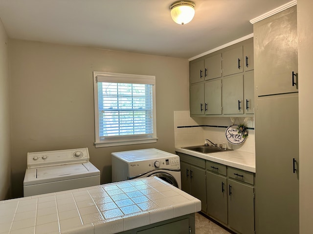 washroom with cabinet space, a sink, and independent washer and dryer