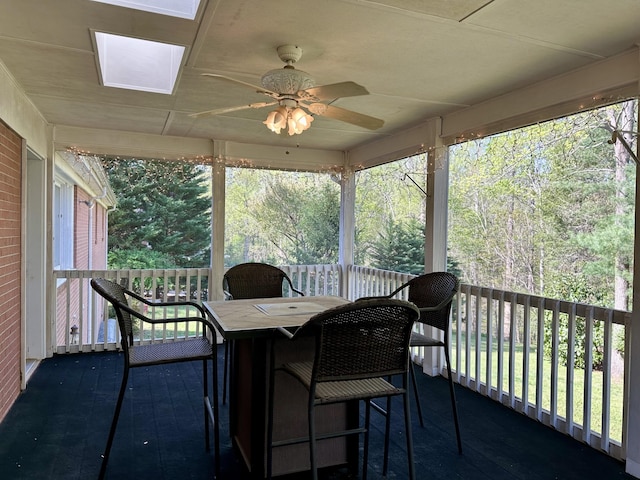 sunroom with a ceiling fan, outdoor dining area, and a skylight