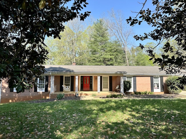 ranch-style home with brick siding, a chimney, a front lawn, and covered porch