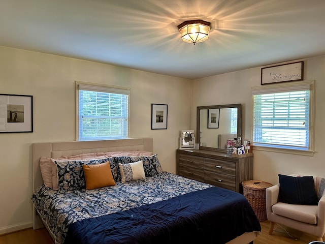 bedroom with wood finished floors and multiple windows