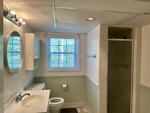 full bath with wainscoting, a sink, a shower stall, and toilet