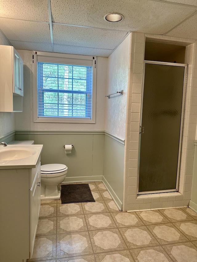 full bathroom featuring tile patterned floors, toilet, vanity, a paneled ceiling, and a stall shower