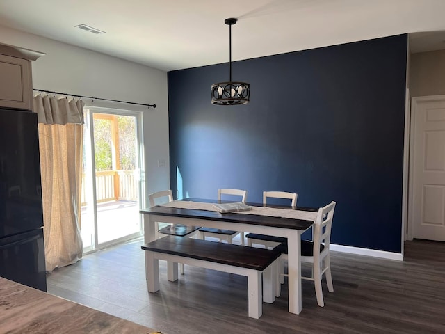 dining area with baseboards, wood finished floors, visible vents, and a chandelier